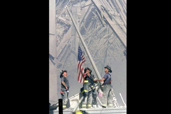 Firemen raise a United States flag where the World Trade Center formerly stood. 