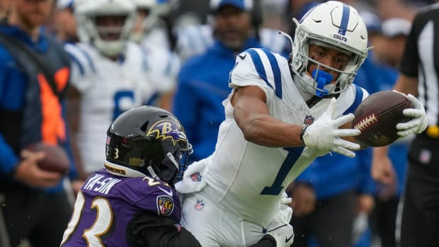 Colts wide receiver Josh Downs (white jersey and helmet with blue number) runs through a Ravens defender (purple jersey). 