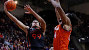 Jan 4, 2025; Blacksburg, Virginia, USA; Miami Hurricanes guard Divine Ugochukwu (99) shoots the ball against Virginia Tech Hokies forward Mylyjael Poteat (34) during the second half at Cassell Coliseum. Mandatory Credit: Peter Casey-Imagn Images
