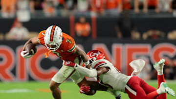 Oct 17, 2025; Miami Gardens, Florida, USA; Miami Hurricanes wide receiver CJ Daniels (7) carries the football against Louisville Cardinals cornerback Justin Agu (13) during the fourth quarter at Hard Rock Stadium. Mandatory Credit: Sam Navarro-Imagn Images