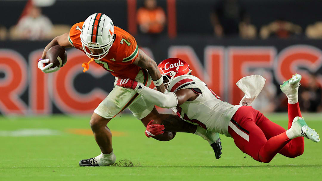 Oct 17, 2025; Miami Gardens, Florida, USA; Miami Hurricanes wide receiver CJ Daniels (7) carries the football against Louisville Cardinals cornerback Justin Agu (13) during the fourth quarter at Hard Rock Stadium. Mandatory Credit: Sam Navarro-Imagn Images
