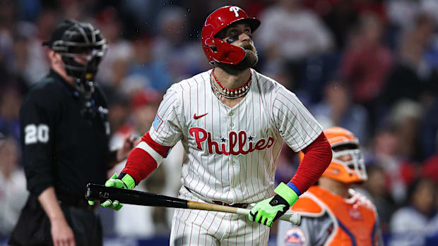 Philadelphia Phillies first base Bryce Harper holds his bat in a white uniform and red helmet