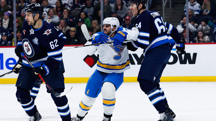 Jan 20, 2026; Winnipeg, Manitoba, CAN; Winnipeg Jets defenseman Logan Stanley (64) jostles for position with St. Louis Blues forward Robby Fabbri (9) during the first period at Canada Life Centre. Mandatory Credit: Terrence Lee-Imagn Images