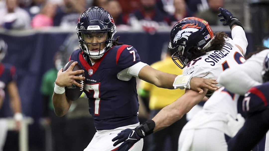 Dec 3, 2023; Houston, Texas, USA; Houston Texans quarterback C.J. Stroud (7) attempts to escape the grasp of Denver Broncos linebacker Alex Singleton (49) during the fourth quarter at NRG Stadium. Mandatory Credit: Troy Taormina-Imagn Images