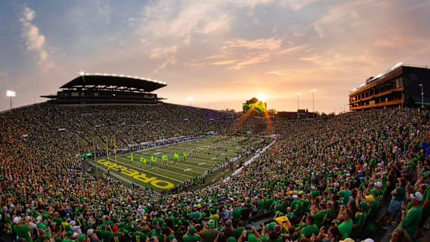 The sun sets over Autzen Stadium as Oregon players and cheerleaders take the field for the game against Boise State in Eugene