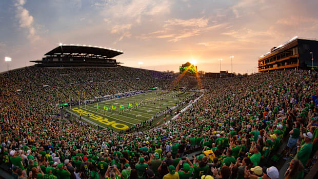 The sun sets over Autzen Stadium as Oregon players and cheerleaders take the field for the game against Boise State in Eugen