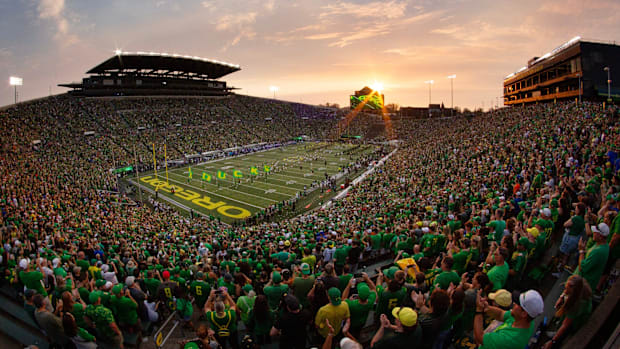 The sun sets over Autzen Stadium as Oregon players and cheerleaders take the field for the game against Boise State in