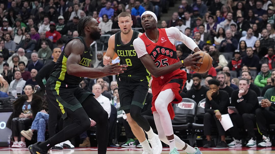 Jan 15, 2025; Toronto, Ontario, CAN; Toronto Raptors forward Chris Boucher (25) drives against Boston Celtics forward Jaylen Brown (7) and center Kristaps Porzingis (8) during the second half at Scotiabank Arena. Mandatory Credit: John E. Sokolowski-Imagn Images