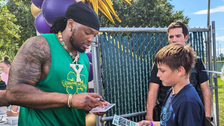 Baltimore Ravens running back Derrick Henry signs a magazine for a young fan at the Two-All Carnivall in Yulee on June 29, 2024. [Clayton Freeman/Florida Times-Union]