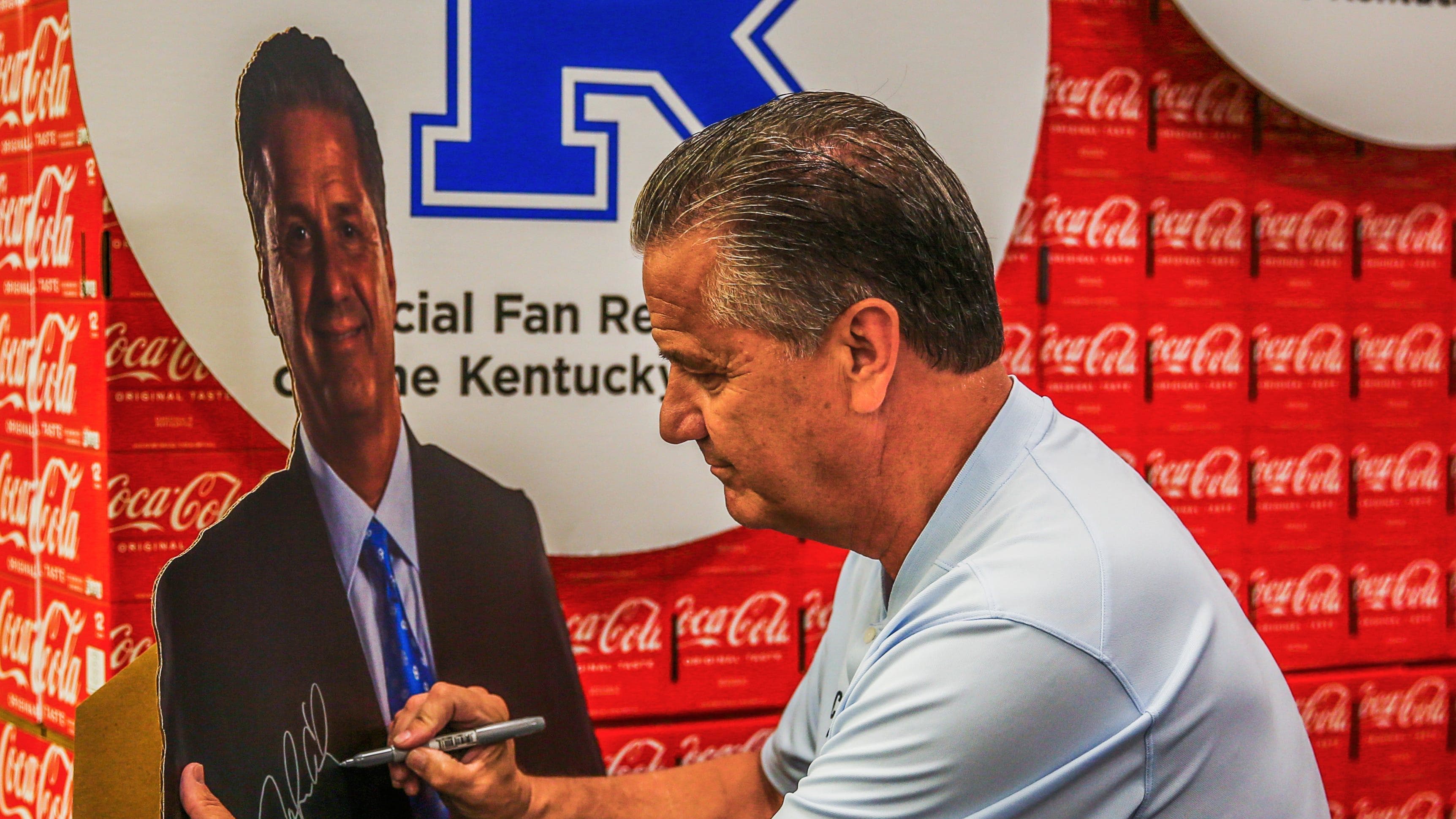 Former Kentucky men's head basketball coach John Calipari autographs a standing poster of himself at a Kroger.
