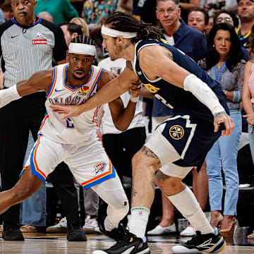 Oklahoma City Thunder guard Shai Gilgeous-Alexander controls the ball as Denver Nuggets forward Aaron Gordon guards.
