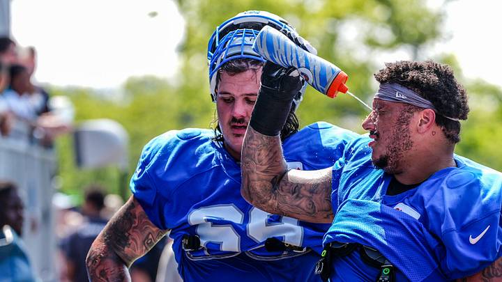 Detroit Lions guard Christian Mahogany squirts water in his face alongside guard Tate Ratledge (standing) and tackle Penei Sewell (sitting) at the end of joint practice with the Miami Dolphins at Lions headquarters and training facility in Allen Park, Thursday, Aug. 14, 2025.