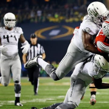 Ohio State Buckeyes running back Ezekiel Elliott (15) lunges toward the goal line, but is tackled just short by Oregon Ducks defensive back Reggie Daniels (8) and linebacker Tony Washington (91) during the first quarter of the College Football Playoff National Championship at AT&T Stadium in Arlington, Texas on Jan. 12, 2015. 