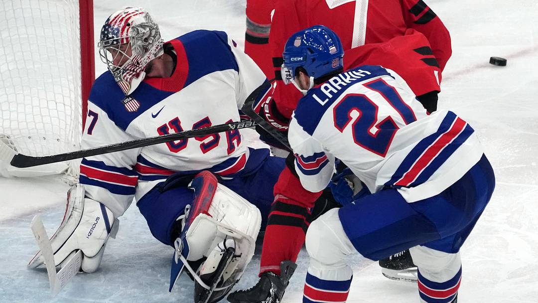 Feb 22, 2026; Milan, Italy; Connor Hellebuyck (37) of the United States defends against Devon Toews (7) of Canada as Dylan Larkin (21) and Mark Stone (61) and Mitch Marner (93) look on during the men's ice hockey gold medal game during the Milano Cortina 2026 Olympic Winter Games at Milano Santagiulia Ice Hockey Arena. Mandatory Credit: James Lang-Imagn Images