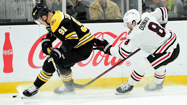 Apr 10, 2025; Boston, Massachusetts, USA;  Boston Bruins defenseman Nikita Zadorov (91) tries to gain control of the puck while Chicago Blackhawks center Ryan Donato (8) defends during the second period at TD Garden. Mandatory Credit: Bob DeChiara-Imagn Images