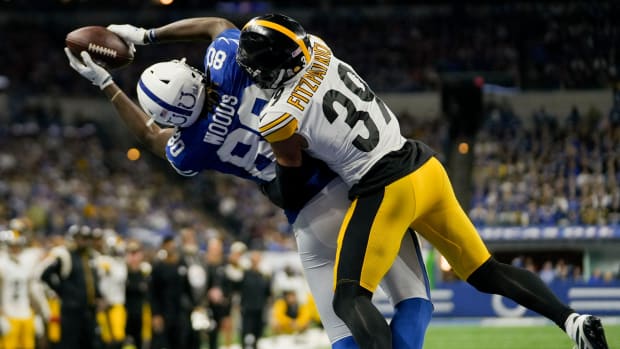 Colts tight end Jelani Woods battles for a catch against a defender (black/yellow) wearing a blue jersey and white helmet.