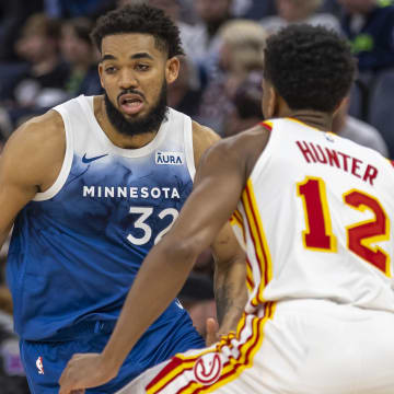 Apr 12, 2024; Minneapolis, Minnesota, USA; Minnesota Timberwolves center Karl-Anthony Towns (32) dribbles the ball as Atlanta Hawks forward De'Andre Hunter (12) plays defense in the second half at Target Center. Mandatory Credit: Jesse Johnson-USA TODAY Sports