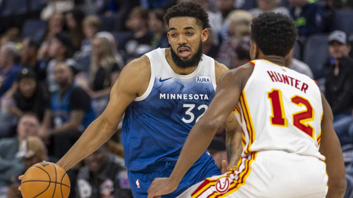 Apr 12, 2024; Minneapolis, Minnesota, USA; Minnesota Timberwolves center Karl-Anthony Towns (32) dribbles the ball as Atlanta Hawks forward De'Andre Hunter (12) plays defense in the second half at Target Center. Mandatory Credit: Jesse Johnson-USA TODAY Sports