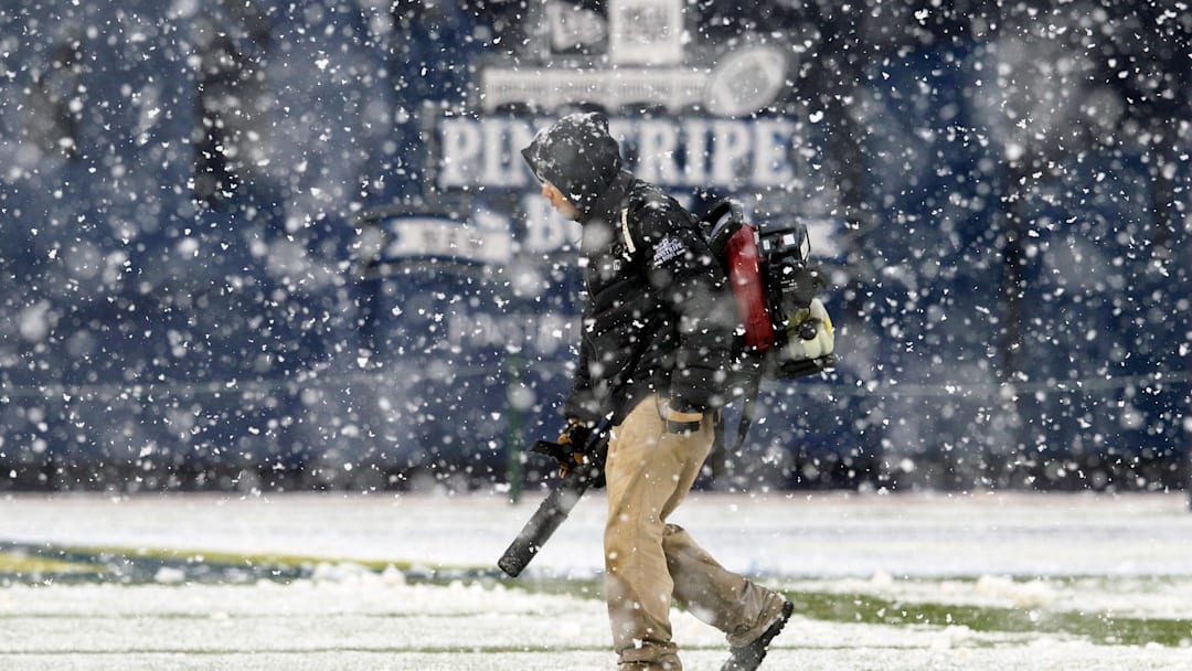 A member of the Yankee Stadium grounds crew blows snow off the yard lines before the start of the 2012 Pinstripe Bowl game between the Syracuse Orange and the West Virginia Mountaineers at Yankee Stadium.