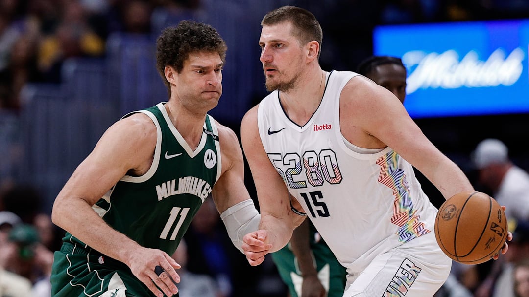 Mar 26, 2025; Denver, Colorado, USA; Denver Nuggets center Nikola Jokic (15) controls the ball as Milwaukee Bucks center Brook Lopez (11) guards in the fourth quarter at Ball Arena. Mandatory Credit: Isaiah J. Downing-Imagn Images