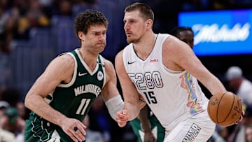Mar 26, 2025; Denver, Colorado, USA; Denver Nuggets center Nikola Jokic (15) controls the ball as Milwaukee Bucks center Brook Lopez (11) guards in the fourth quarter at Ball Arena. Mandatory Credit: Isaiah J. Downing-Imagn Images