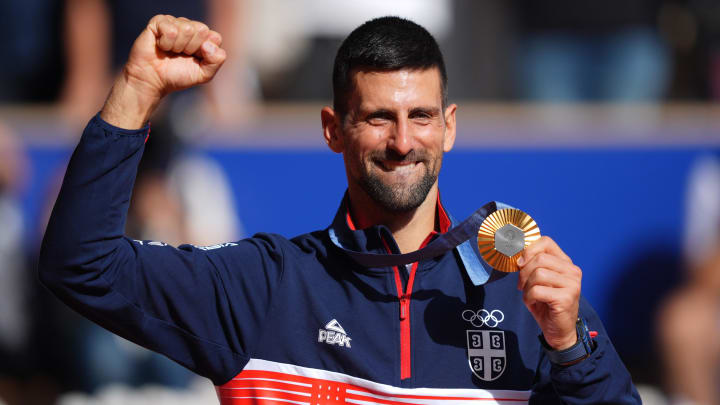 Novak Djokovic celebrates after receiving his gold medal