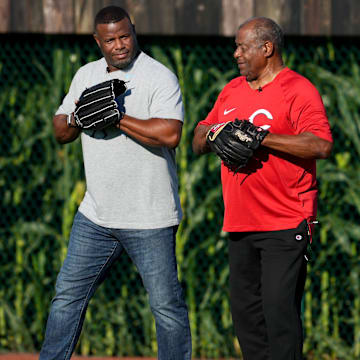 Hall of Fame baseball player and former Cincinnati Reds center fielder Ken Griffey Jr., left, asks his dad and fellow  Hall of Fame player Ken Griffey Sr., if he  d like to play catch  before a baseball game between the Chicago Cubs and the Cincinnati Reds, Thursday, Aug. 11, 2022, at the MLB Field of Dreams stadium in Dyersville, Iowa