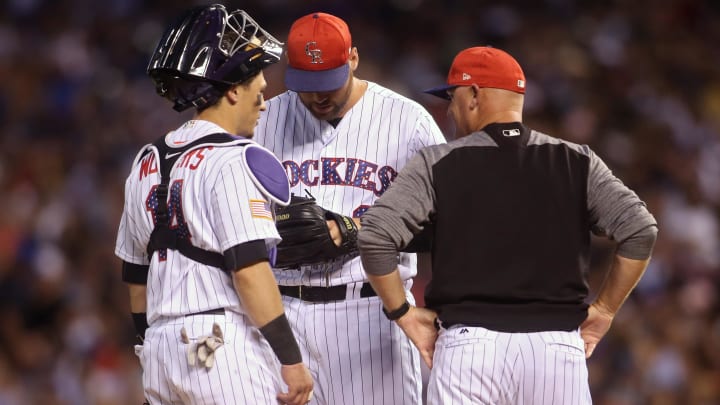 Jul 4, 2017; Denver, CO, USA; Colorado Rockies relief pitcher Jordan Lyles (24) talks with catcher Tony Wolters (14) and pitching coach Steve Foster (right) during the eighth inning at Coors Field. Mandatory Credit: Chris Humphreys-USA TODAY Sports