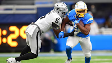 Oct 1, 2023; Inglewood, California, USA; Los Angeles Chargers running back Joshua Kelley (25) runs the ball against Las Vegas Raiders linebacker Divine Deablo (5) during the first half at SoFi Stadium. Mandatory Credit: Gary A. Vasquez-Imagn Images