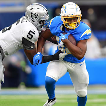 Oct 1, 2023; Inglewood, California, USA; Los Angeles Chargers running back Joshua Kelley (25) runs the ball against Las Vegas Raiders linebacker Divine Deablo (5) during the first half at SoFi Stadium. Mandatory Credit: Gary A. Vasquez-Imagn Images