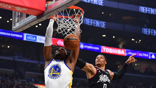 Mar 15, 2023; Los Angeles, California, USA; Golden State Warriors forward Kevon Looney (5) dunks for the basket ahead of Los Angeles Clippers guard Russell Westbrook (0) during the first half at Crypto.com Arena. Mandatory Credit: Gary A. Vasquez-USA TODAY Sports