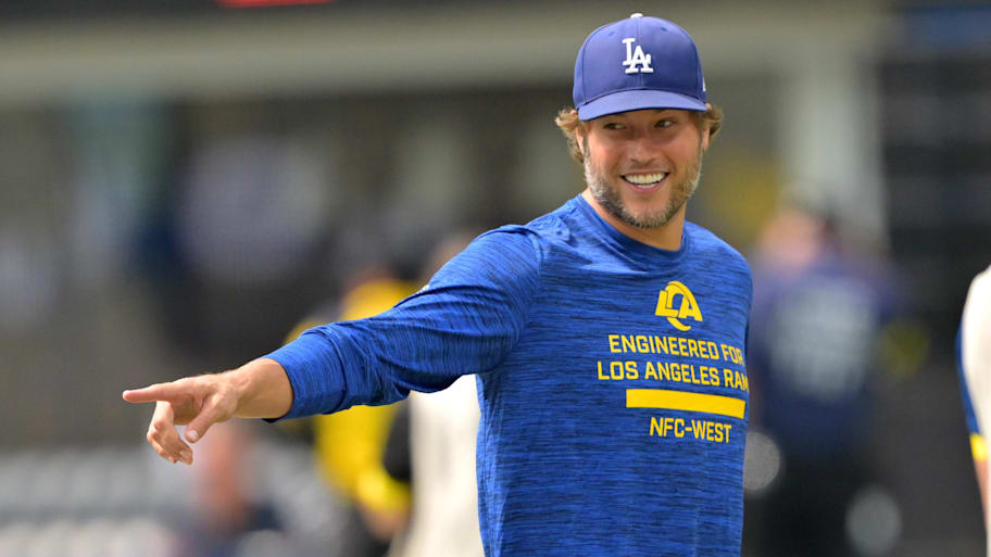Matthew Stafford smiling and pointing, wearing a Dodgers hat