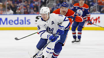 Feb 1, 2025; Edmonton, Alberta, CAN; Toronto Maple Leafs forward Mitch Marner (16) and Edmonton Oilers forward Zach Hyman (18) chase a loose puck during the third period at Rogers Place. Mandatory Credit: Perry Nelson-Imagn Images