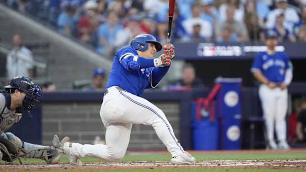 Varsho hitting a ball in white pants and a blue jerse