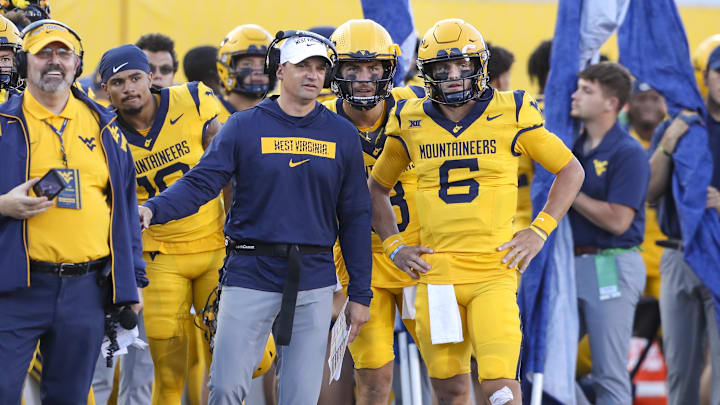 Sep 7, 2024; Morgantown, West Virginia, USA; West Virginia Mountaineers head coach Neal Brown talks with West Virginia Mountaineers quarterback Garrett Greene (6) after he threw for a touchdown during the second quarter against the Albany Great Danes at Mountaineer Field at Milan Puskar Stadium. Mandatory Credit: Ben Queen-Imagn Images