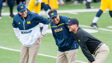 Michigan Wolverines' tight end coach Jay Harbaugh (left), quarterbacks coach Jedd Fisch (middle) and head coach Jim Harbaugh (right) watch their football team warmup ahead of a regular season game during the 2015 college football season.