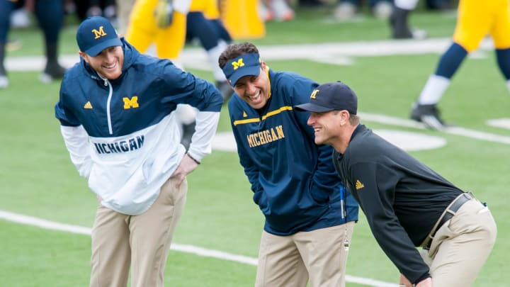 Michigan Wolverines' tight end coach Jay Harbaugh (left), quarterbacks coach Jedd Fisch (middle) and head coach Jim Harbaugh (right) watch their football team warmup ahead of a regular season game during the 2015 college football season.