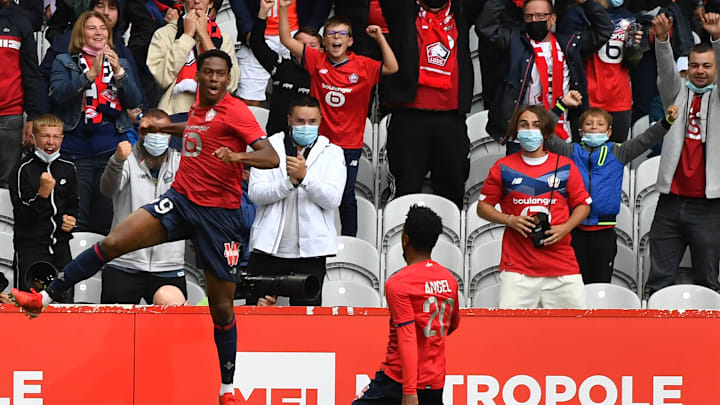 Jonathan David celebrates whilst being closely watched by Angel Gomes - two rumoured Spurs targets 