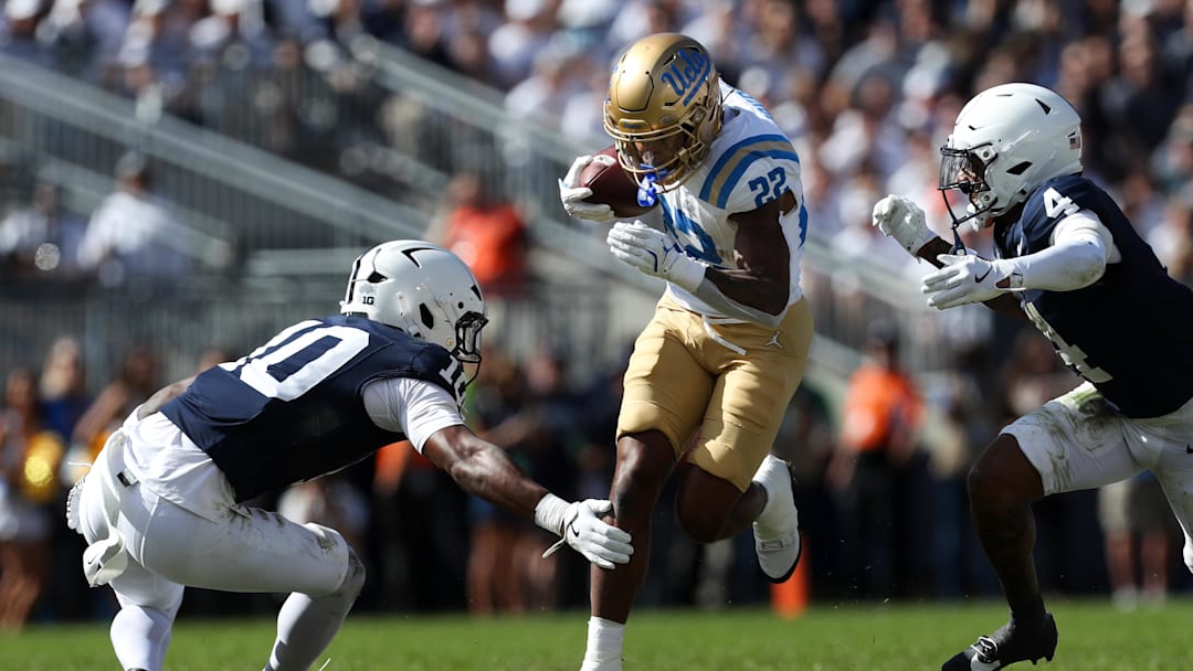 Oct 5, 2024; University Park, Pennsylvania, USA; UCLA Bruins running back Keegan Jones (22) runs with the ball while attempting to avoid a tackle by Penn State Nittany Lions safety Dejuan Lane (10) during the fourth quarter at Beaver Stadium. Mandatory Credit: Matthew O'Haren-Imagn Images