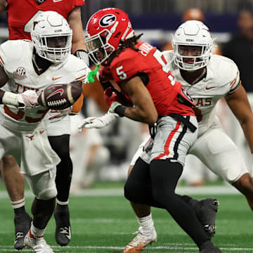 Dec 7, 2024; Atlanta, GA, USA; Texas Longhorns linebacker David Gbenda (33) causes a fumble on Georgia Bulldogs wide receiver Anthony Evans III (5) during the second half in the 2024 SEC Championship game at Mercedes-Benz Stadium. Mandatory Credit: Brett Davis-Imagn Images