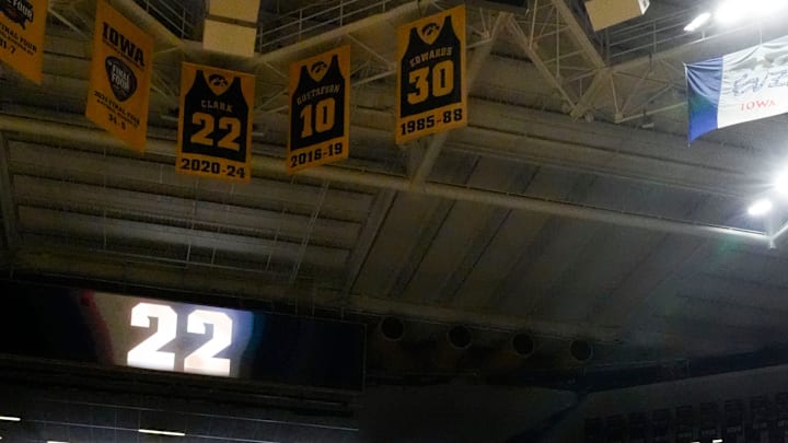 Caitlin Clark is pictured at half court as her retired jersey hangs in the rafters behind her at Carver-Hawkeye Arena in Iowa