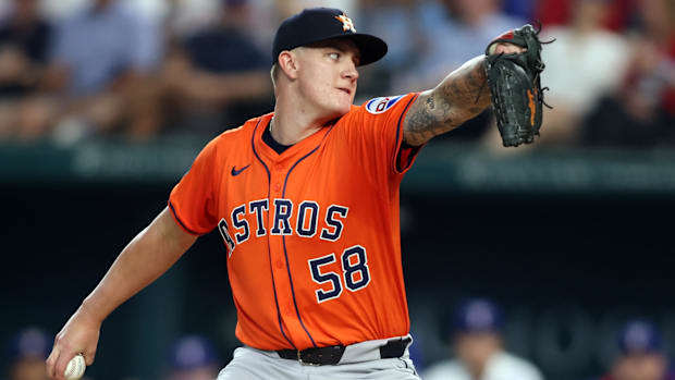 Houston Astros pitcher Hunter Brown throws in an orange jersey and blue hat