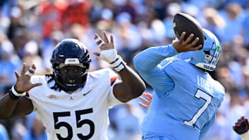 Oct 25, 2025; Chapel Hill, North Carolina, USA; North Carolina Tar Heels quarterback Gio Lopez (7) passes the ball as Virginia Cavaliers defensive tackles Anthony Britton (55) and Jason Hammond (91) pressure in the first quarter at Kenan Stadium. Mandatory Credit: Bob Donnan-Imagn Images