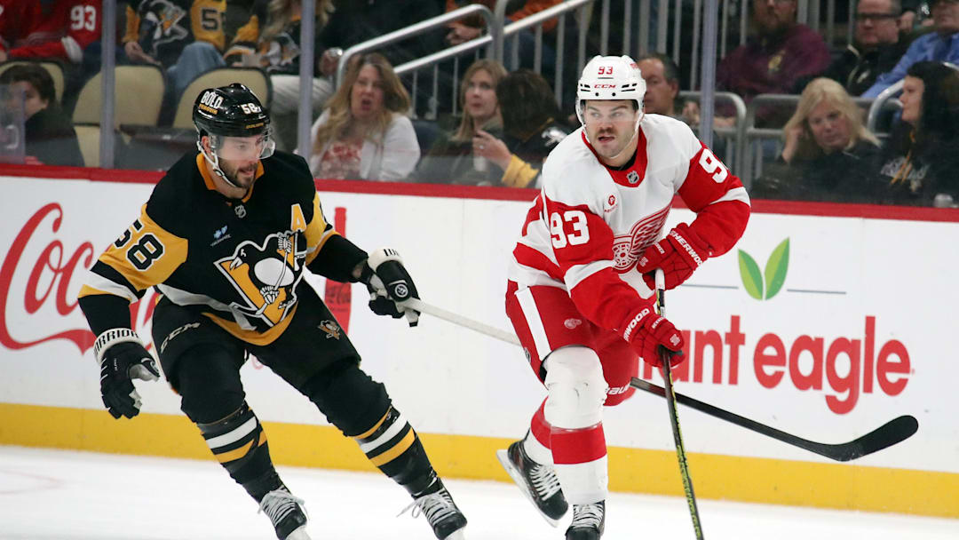 Nov 13, 2024; Pittsburgh, Pennsylvania, USA;  Detroit Red Wings right wing Alex DeBrincat (93) skates with the puck against Pittsburgh Penguins defenseman Kris Letang (58) during the first period at PPG Paints Arena. Mandatory Credit: Charles LeClaire-Imagn Images