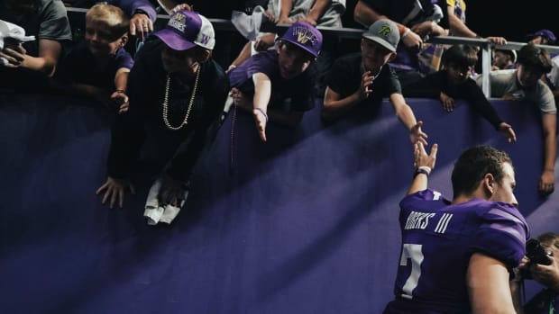 Quarterback Will Rogers slaps hands with young fans.