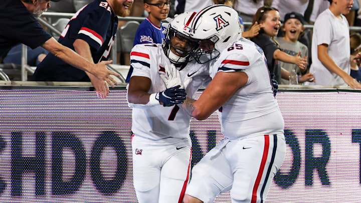 Aug 31, 2024; Tucson, Arizona, USA; Arizona Wildcats running back Jacory Croskey-Merritt (1) celebrates a touchdown with fans and Arizona Wildcats offensive lineman Leif Magnuson during the fourth quarter at Arizona Stadium.