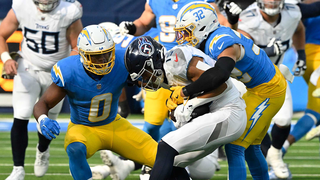 Nov 10, 2024; Inglewood, California, USA; Los Angeles Chargers linebacker Daiyan Henley (0) and safety Alohi Gilman (32) tackle Tennessee Titans wide receiver Nick Westbrook-Ikhine (15) during the second quarter at SoFi Stadium. Mandatory Credit: Robert Hanashiro-Imagn Images