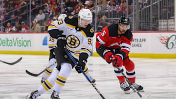 Apr 8, 2025; Newark, New Jersey, USA; Boston Bruins center Fraser Minten (93) skates with the puck as New Jersey Devils defenseman Brenden Dillon (5) defends during the third period at Prudential Center. Mandatory Credit: Ed Mulholland-Imagn Images