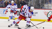 Apr 5, 2025; Newark, New Jersey, USA; New York Rangers right wing Gabe Perreault (94) battles for the puck against the New Jersey Devils during the first period at Prudential Center. Mandatory Credit: Ed Mulholland-Imagn Images