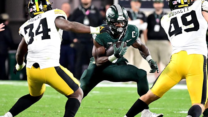 Oct 19, 2024; East Lansing, Michigan, USA;  Michigan State Spartans running back Nate Carter (5) runs against Iowa Hawkeyes linebacker Jay Higgins (34) and defensive lineman Ethan Hurkett (49) in the fourth quarter at Spartan Stadium. Mandatory Credit: Dale Young-Imagn Images